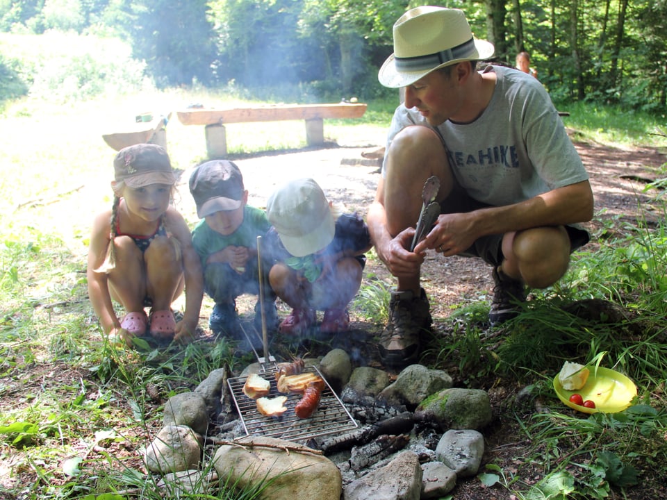 Mann und drei Kinder hocken vor dem Feuer.