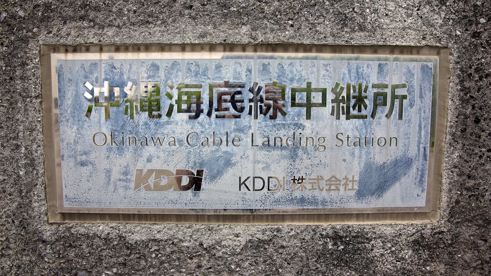 Auf einem Schild steht: «Okinawa Cable Landing Station, KDDI»