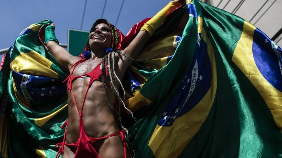 Eine Frau am Karneval in Rio de Janerio hält eine Brasilien-Fahne hoch.