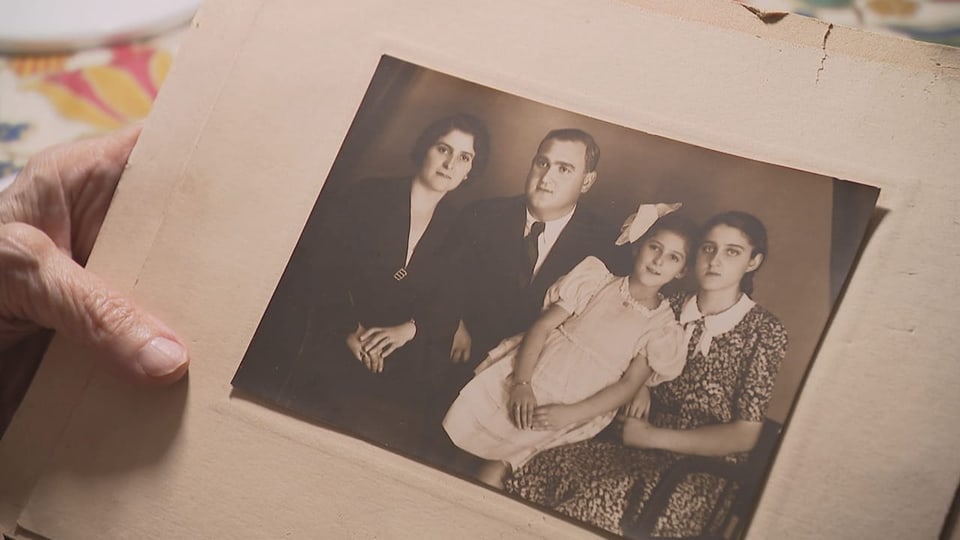 Hand hält Familienfoto mit 4 Personen.
