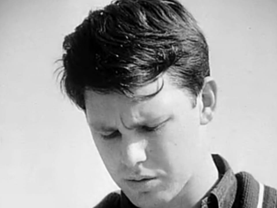 Schwarz-Weiss-Foto des jungen Jim Morrison mit kurzen Haaren.