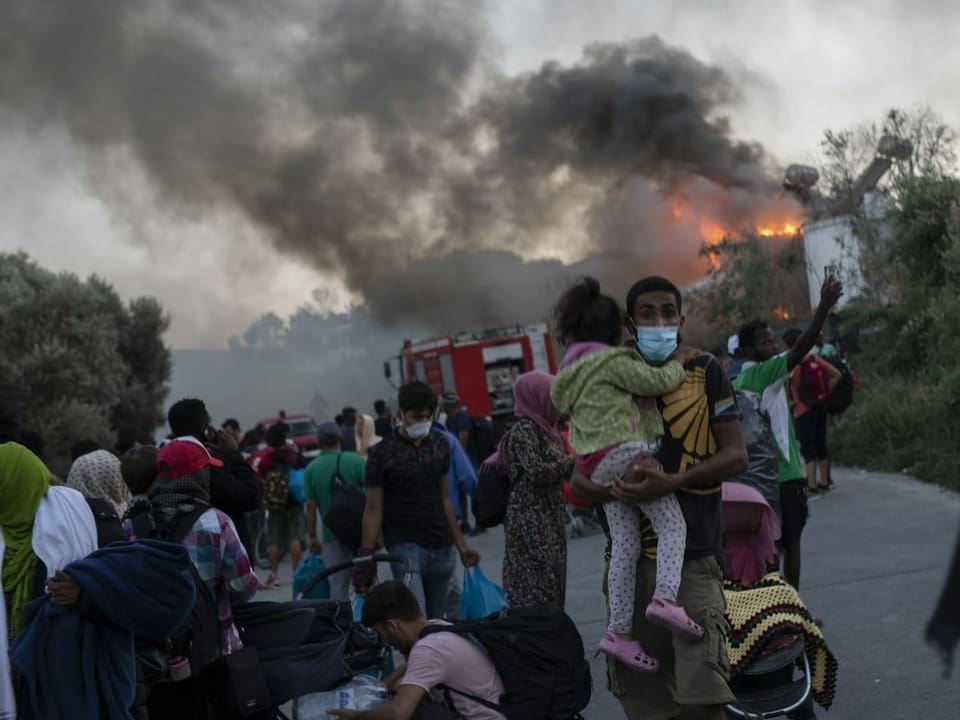 Mann läuft mit Kind aus Flüchtlingslager.