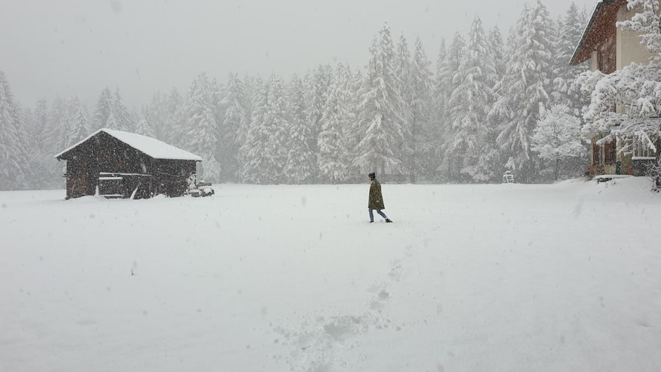 Es schneit und eine Person läuft durch den Schnee.
