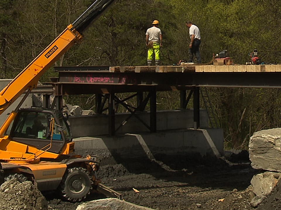 Arbeiter erstellen im Rüfengebiet eine Notbrücke.