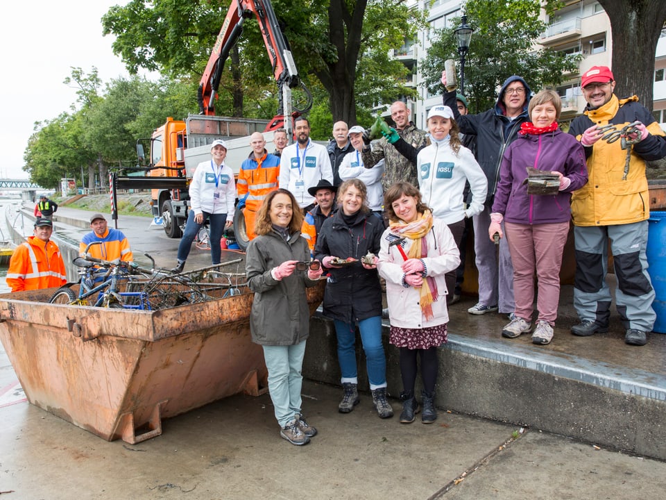 Gruppe von Helferionnen und Helfern posiert neben einer Abfalltonne.