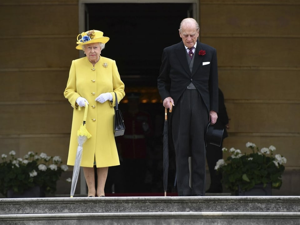 Frau in gelbem Mantel und Mann in schwarzem Anzug auf Treppe