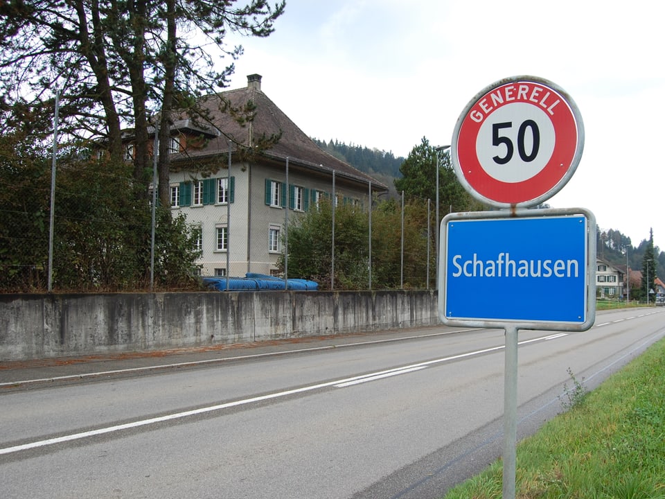 Rechts im BIld die Ortstafel von Schafhausen, links im Hintergrund das alte Schulhaus.