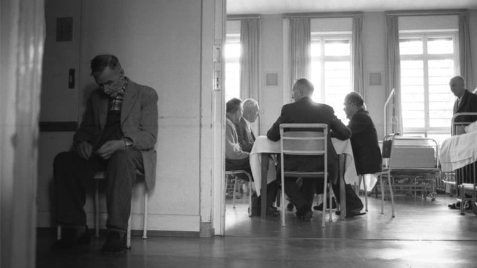 Mann sitzt vor Esszimmer mit gesenktem Kopf