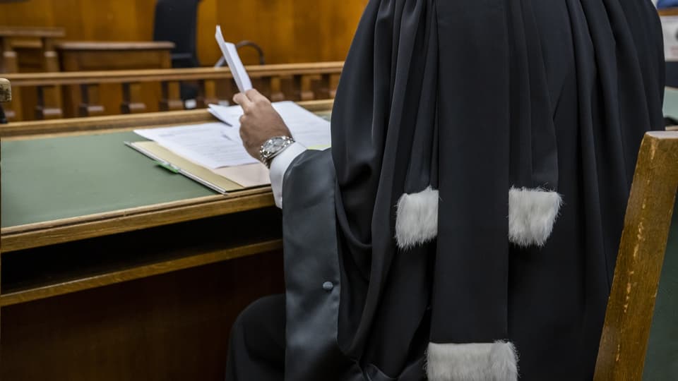 Ein Richter schaut sich in einem Gerichtssaal Akten an.