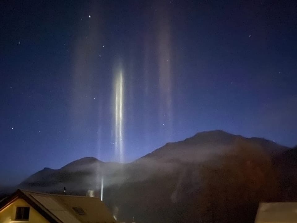 senkrechte Lichter über einem Alpendorf
