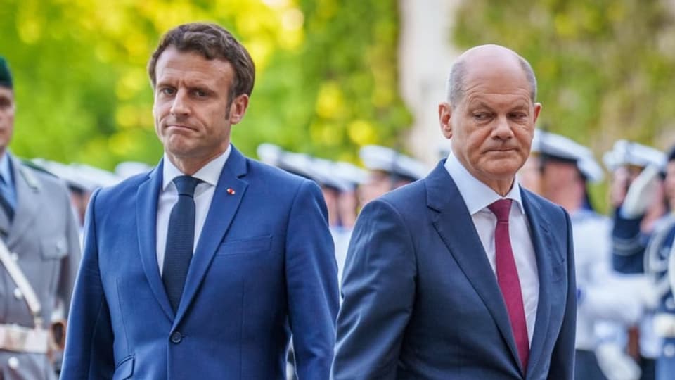 Scholz und Macron stehen sich fast Rücken an Rücken und ziehen eine offenbar enttäuschte Miene.