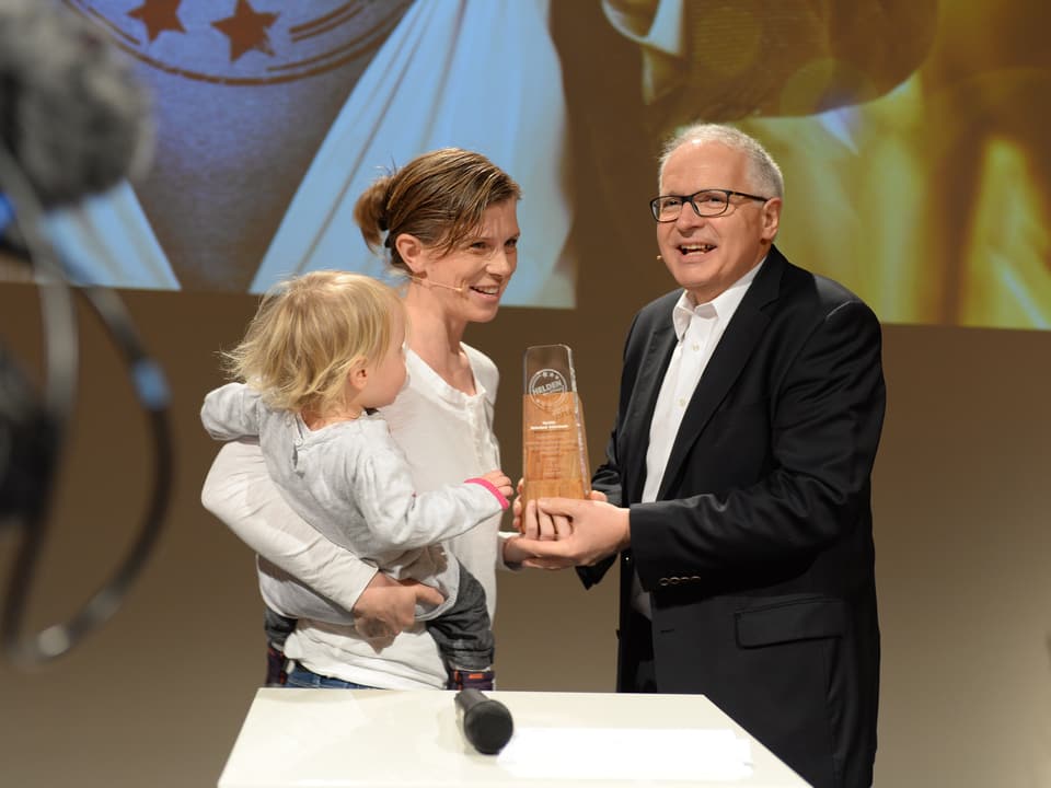 SRF-Direktor Ruedi Matter übergibt Kerstin Birkeland Ackermann den Pokal.