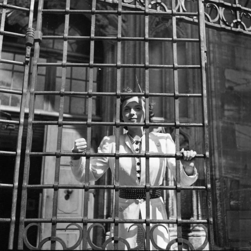 Eine Frau (Jeanette) schaut durch die Gitterstäbe eines Eisentors.