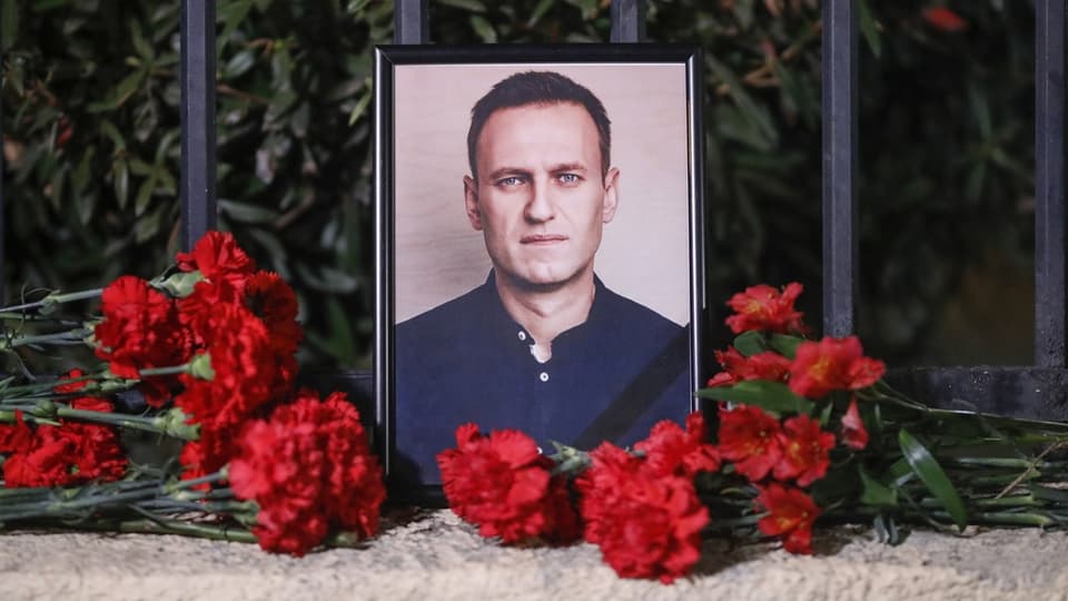 Ein Foto von Nawalny. Davor liegen rote Blumen. 