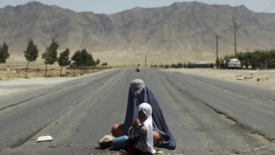 Frau mit Kind bettelt auf Strasse vor Kabul