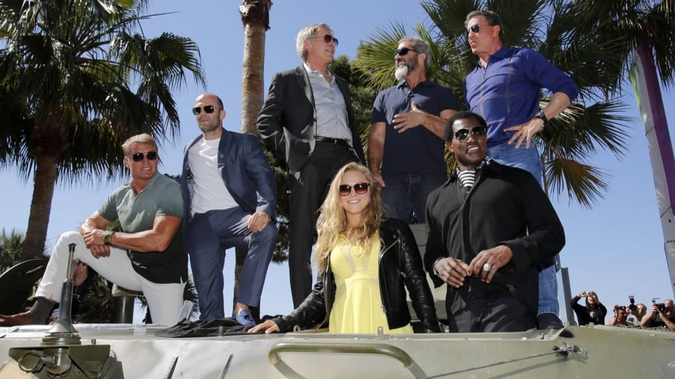 Dolph Lundgren, Jason Statham, Harrison Ford, Ronda Rousey, Mel Gibson, Wesley Snipes und Stallone auf einem Panzer.