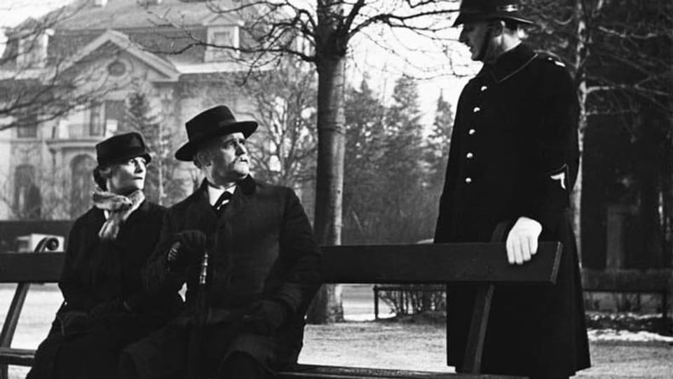 schwarzweiss Bild von einem Paar auf der Bank und einem Polizisten