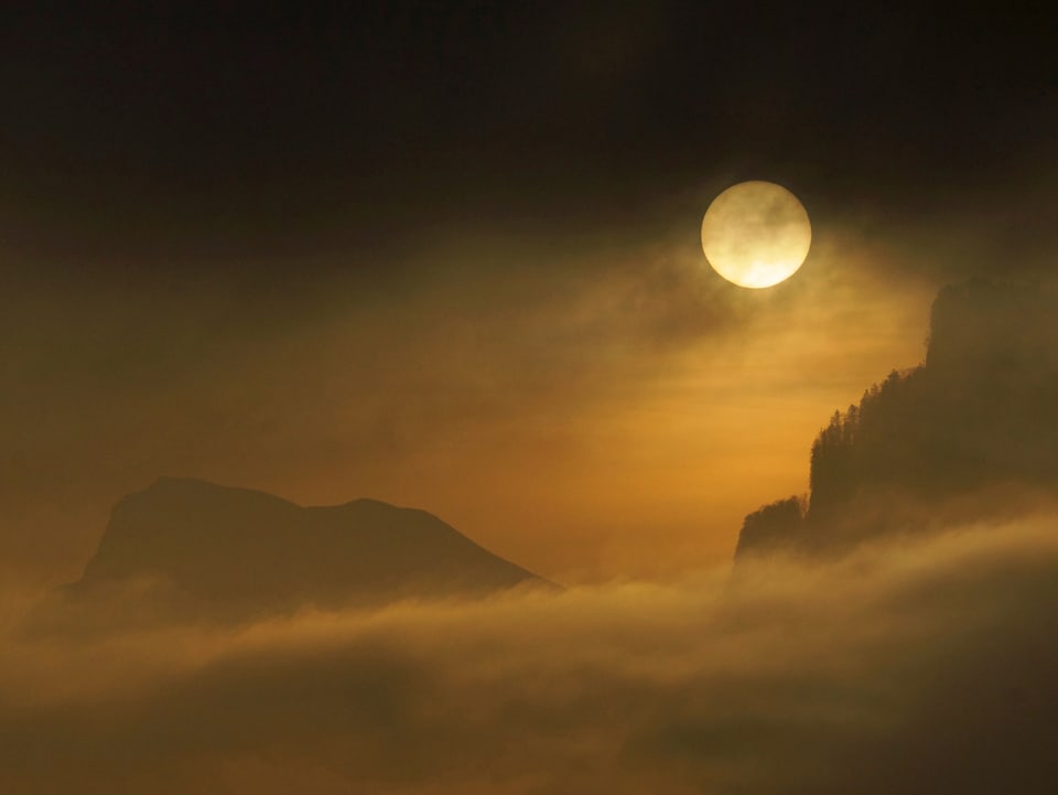 Der Mond bescheint der Nebel im Tal. Der Nebel erscheint als gebliche Suppe.