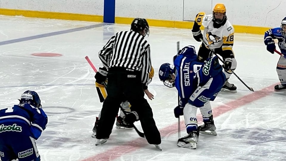 Junioren Eishockeyspieler am Bully mit Schiedsrichter.
