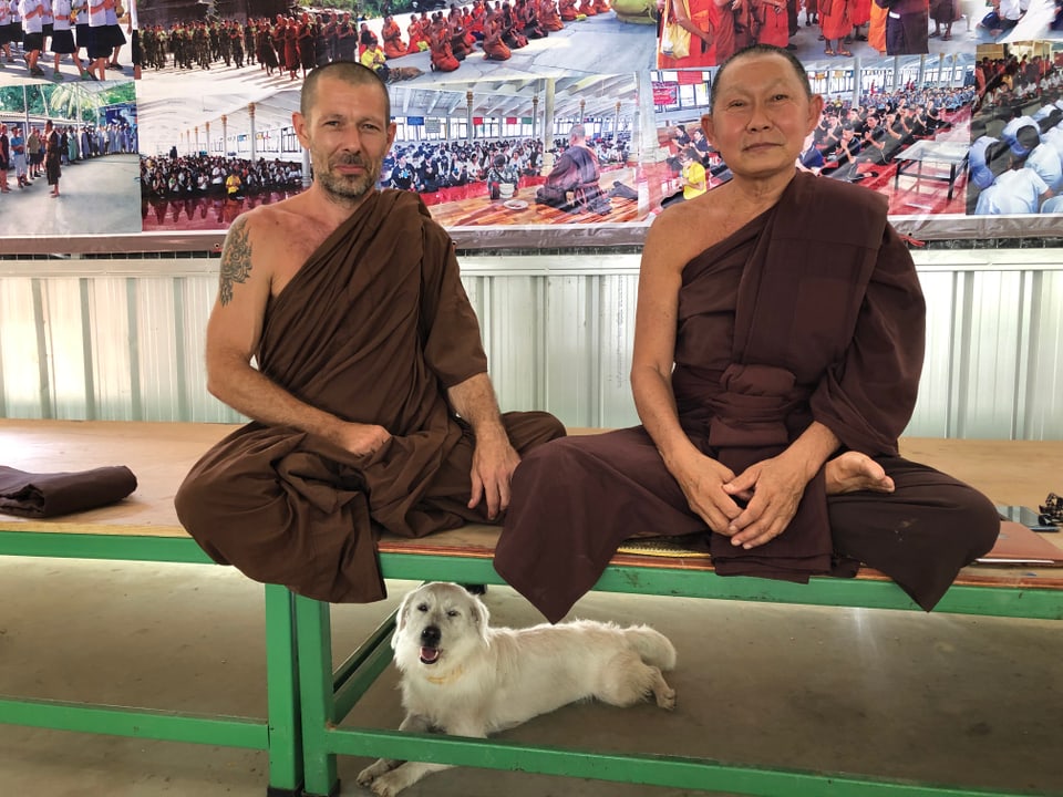 Zwei Mönche im Schneidersitz; Unter ihnen ein Hund.