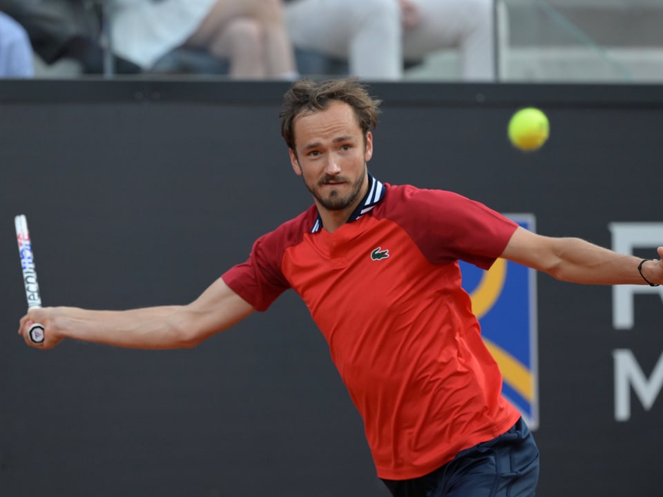 Tennisspieler während eines Spiels in rotem Shirt.