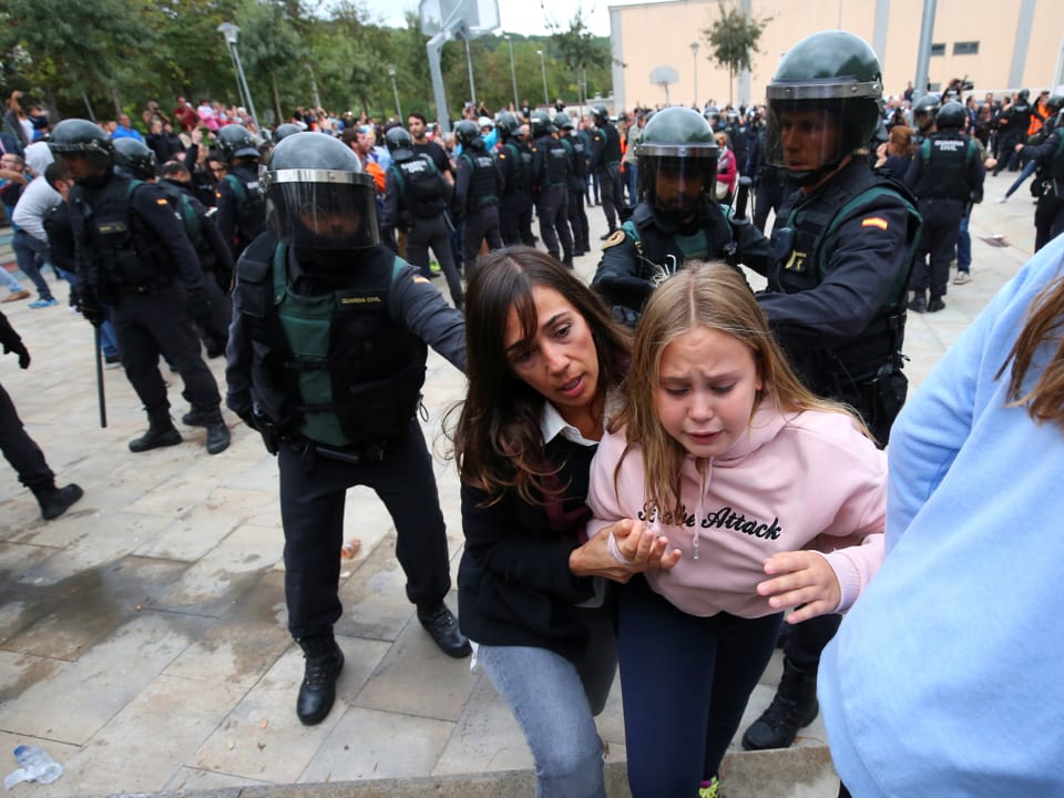 Frau mit Kind werden von Nationalpolizisten auf die Seite gewiesen.