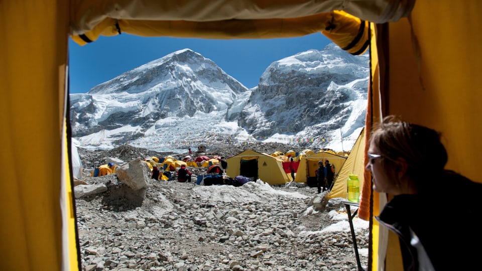 Ausblick auf Zelte und Mount Everest aus einem Zelt heraus.