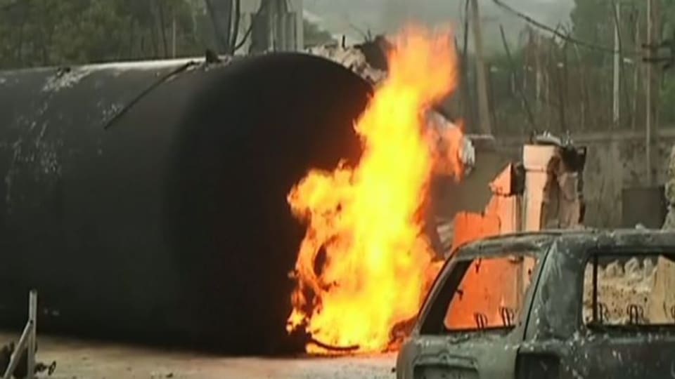Ein Gastankwagen brennt, im Vordergrund ein Auto 