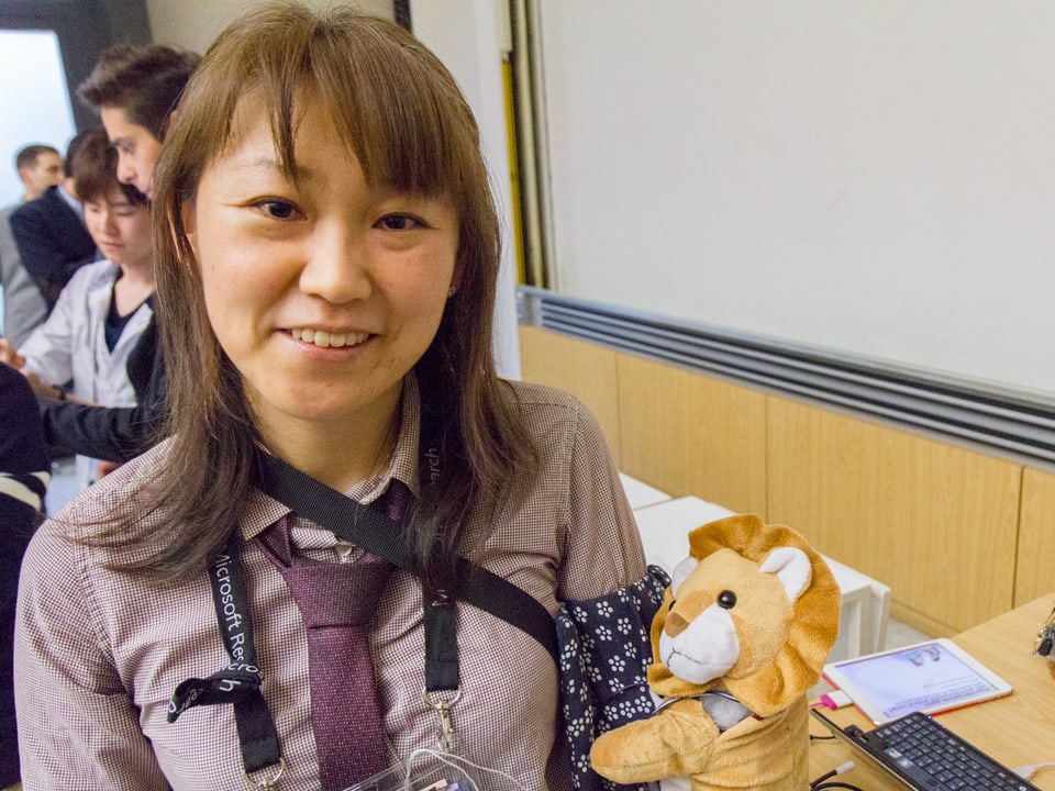 Eine Japanerin mit Teddy-Bär, der auf Berührungen reagiert. 