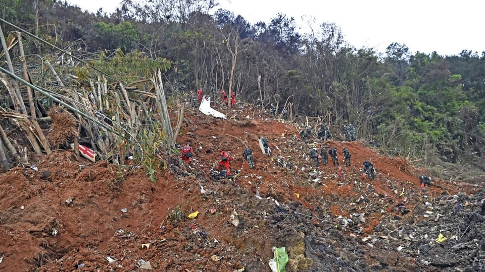 Bergungsleute in der hügeligen Landschaft an der Absturzstelle