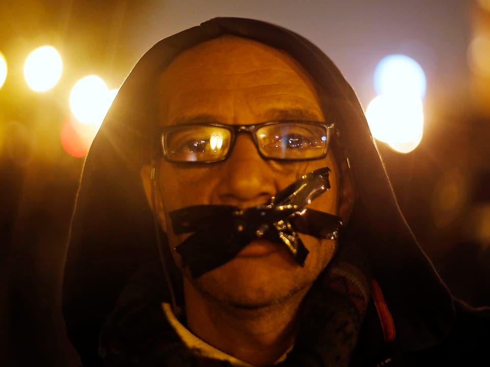 Protestierender mit symbolischem Klebstreifen vor dem Mund