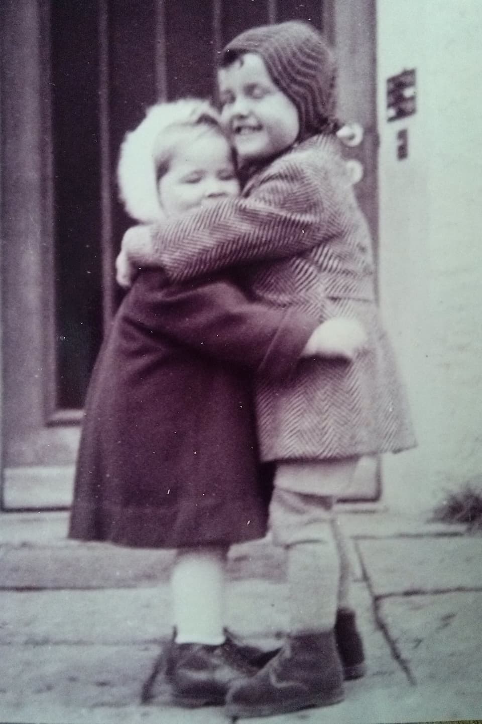 Das Bild zeigt zwei junge Kinder, die sich umarmen. 