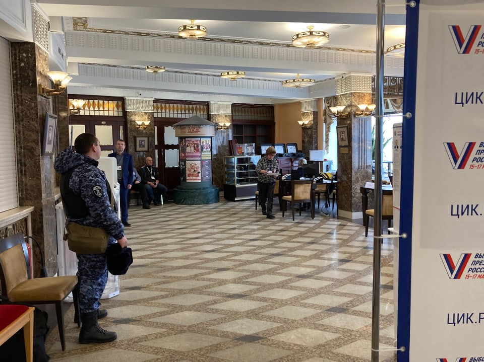 Blick auf ein Foyer des Wahllokals; uniformierter Soldat sichtbar.