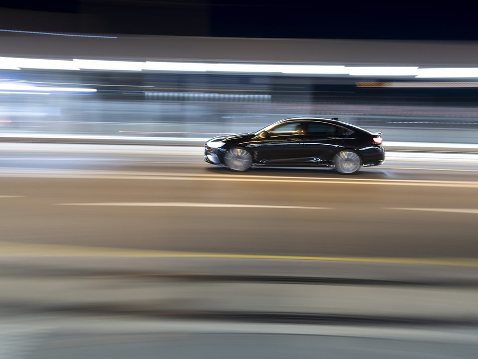 Ein Auto fährt in der Nacht auf der Strasse. Die Lichter sind verschwommen, um die Geschwindigkeit zu illustrieren.