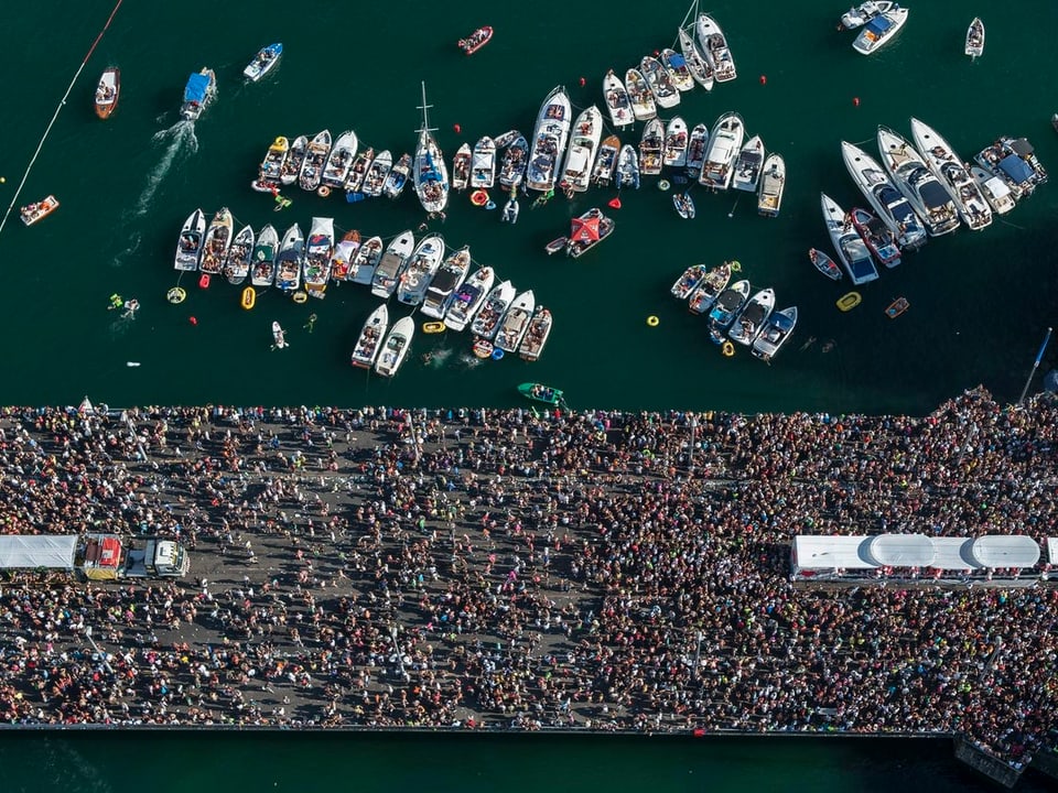 Luftaufnahme der Quaibrücke mit Besuchern und Love Mobiles, im See sind Dutzende Schiffe.