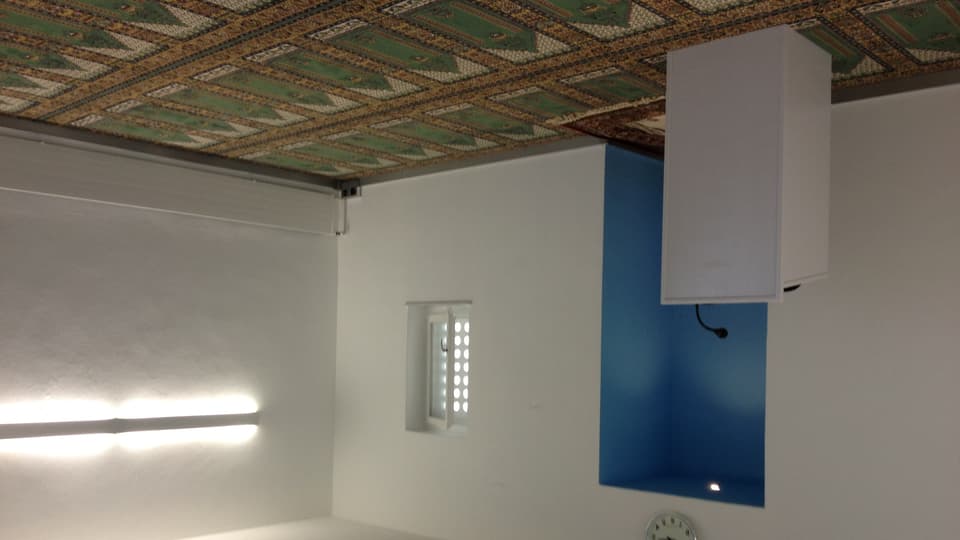 Der Innenraum der Moschee mit Teppich und blauer Gebetsnische.