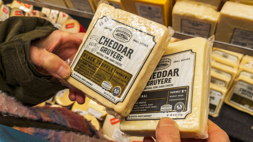 Amerikanischer Gruyère-Käse in den Händen einer einkaufenden Person