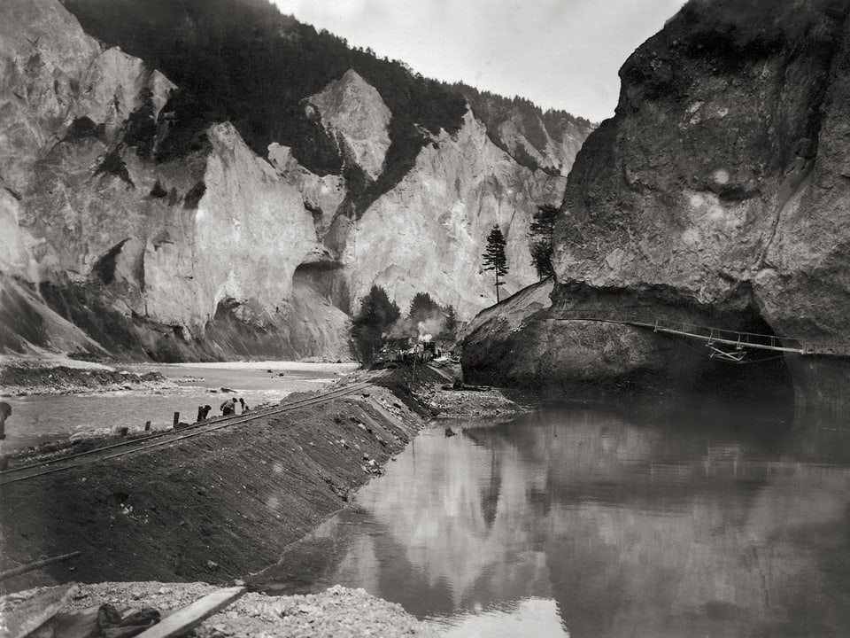 Das Bild zeigt Bauarbeiter beim Errichten eines Damms für die Strecke Reichenau - Iland, die durch die Rheinschlucht führt.
