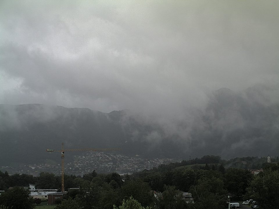 Zwischen den bewaldeten Tessiner Hügeln hängen tiefe graue Wolkenfetzen.