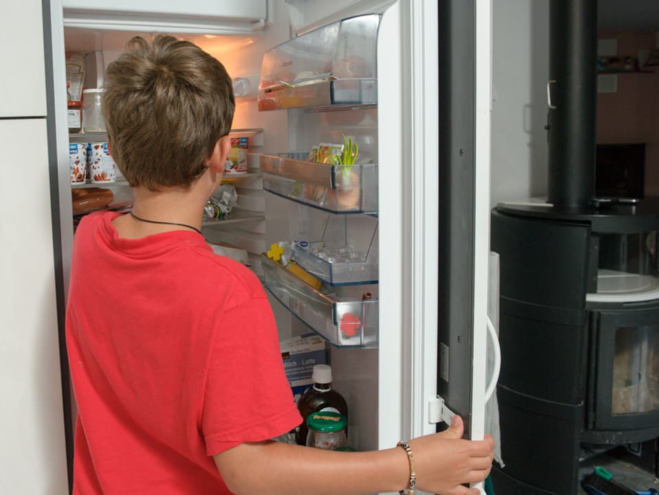 Der 10-jährige Daniele im roten T-Shirt steht vor dem offenen Kühlschrank.