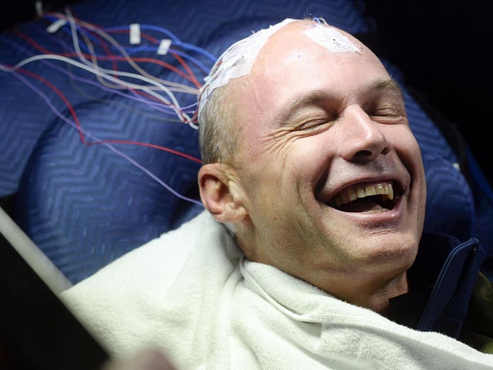  Bertrand Piccard lachend mit Elektroden am Kopf.