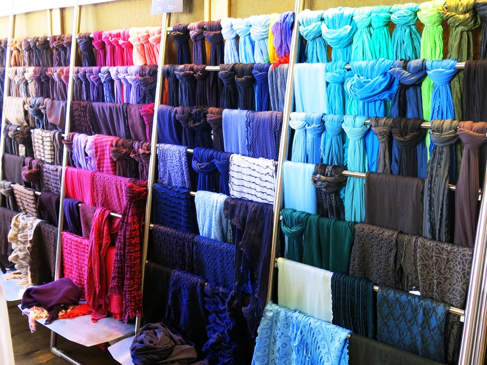 Farbige Kleider und Accessoires hängen über Stangen. 