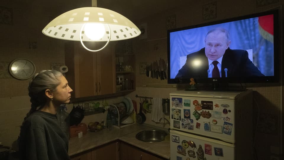 Eine Frau schaut in den Fernseher, Putin spricht.