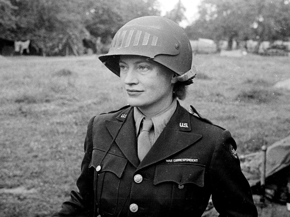 Eie junge Frau mit Militäruniform und Helm blickt geradeaus.