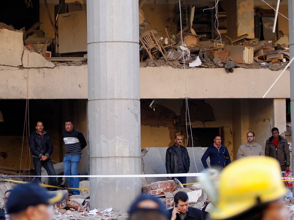 Beamte in Zivil begutachten die Schäden auf einem Stockwerk des angegriffenen Gebäudes.