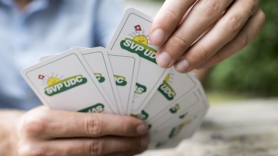 Ein Mann hält ein Kartenspiel mit SVP-Logo in den Händen