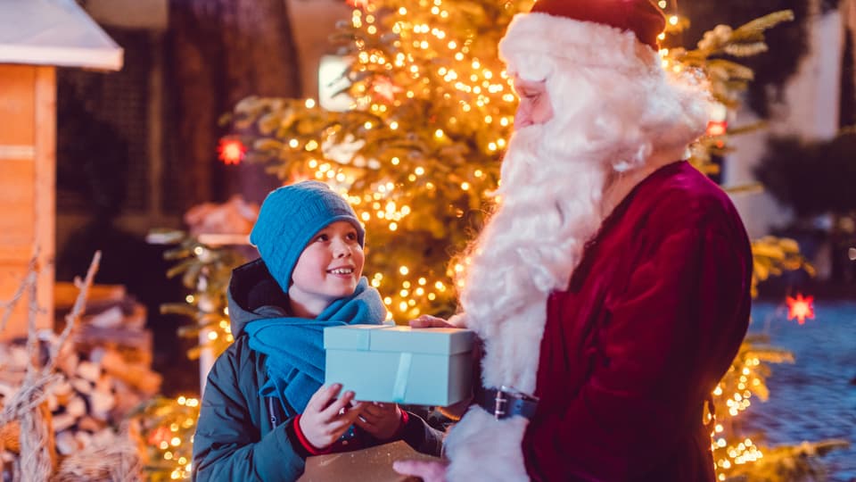 Klassischer Weihnachtsmann übergibt Geschenk an Jungen