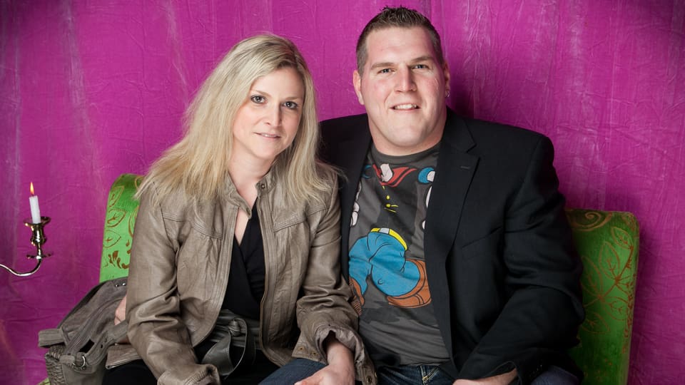 Blonde Frau und Schwinger Christian Stucki sitzen lächelnd auf Sofa
