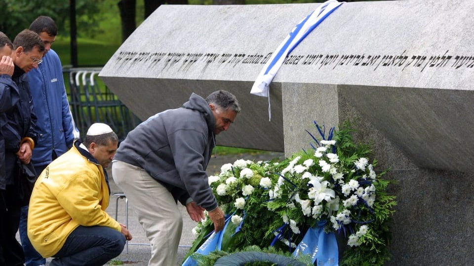 Männer legen Blumen vor dem Denkmal während einer Gedenkzeremonie in der Nähe des Olympischen Dorfes in München nieder.