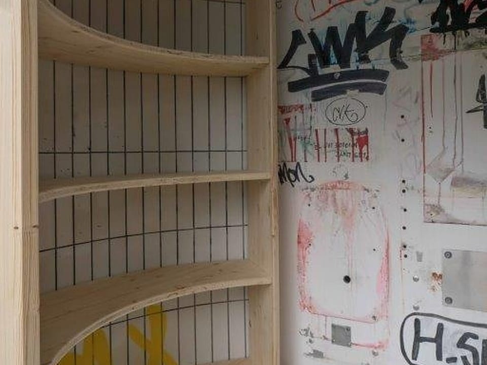 Der Schreiner montiert erste Bücherregale in die ehemalige Telefonkabine. 